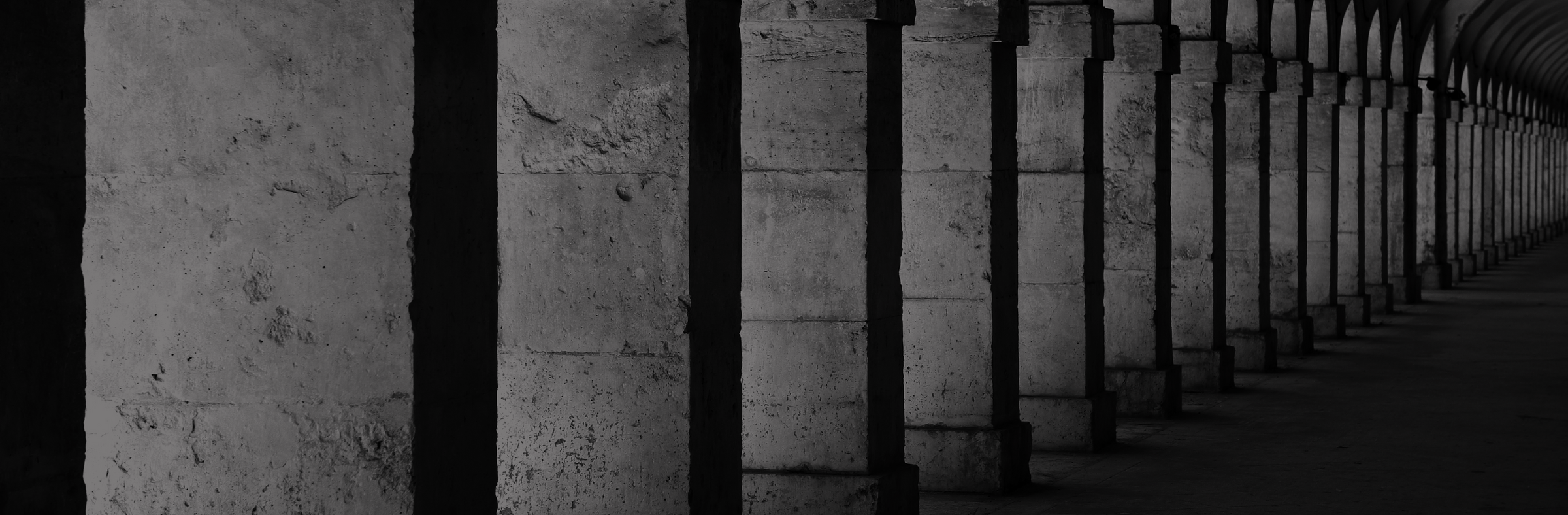 Long stone archway with columns in a dark setting