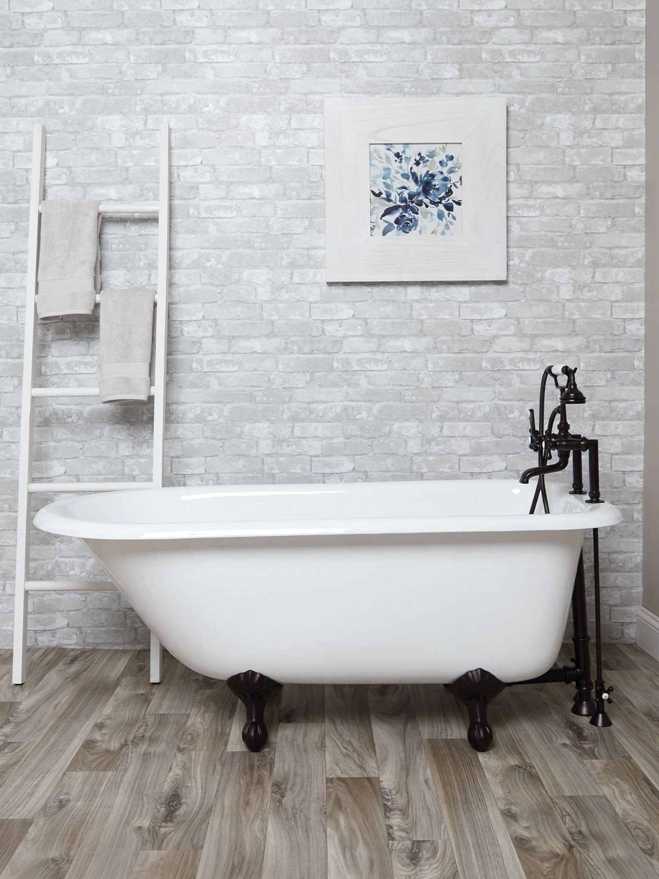 White freestanding bathtub in a bathroom with a decorative wall art piece.