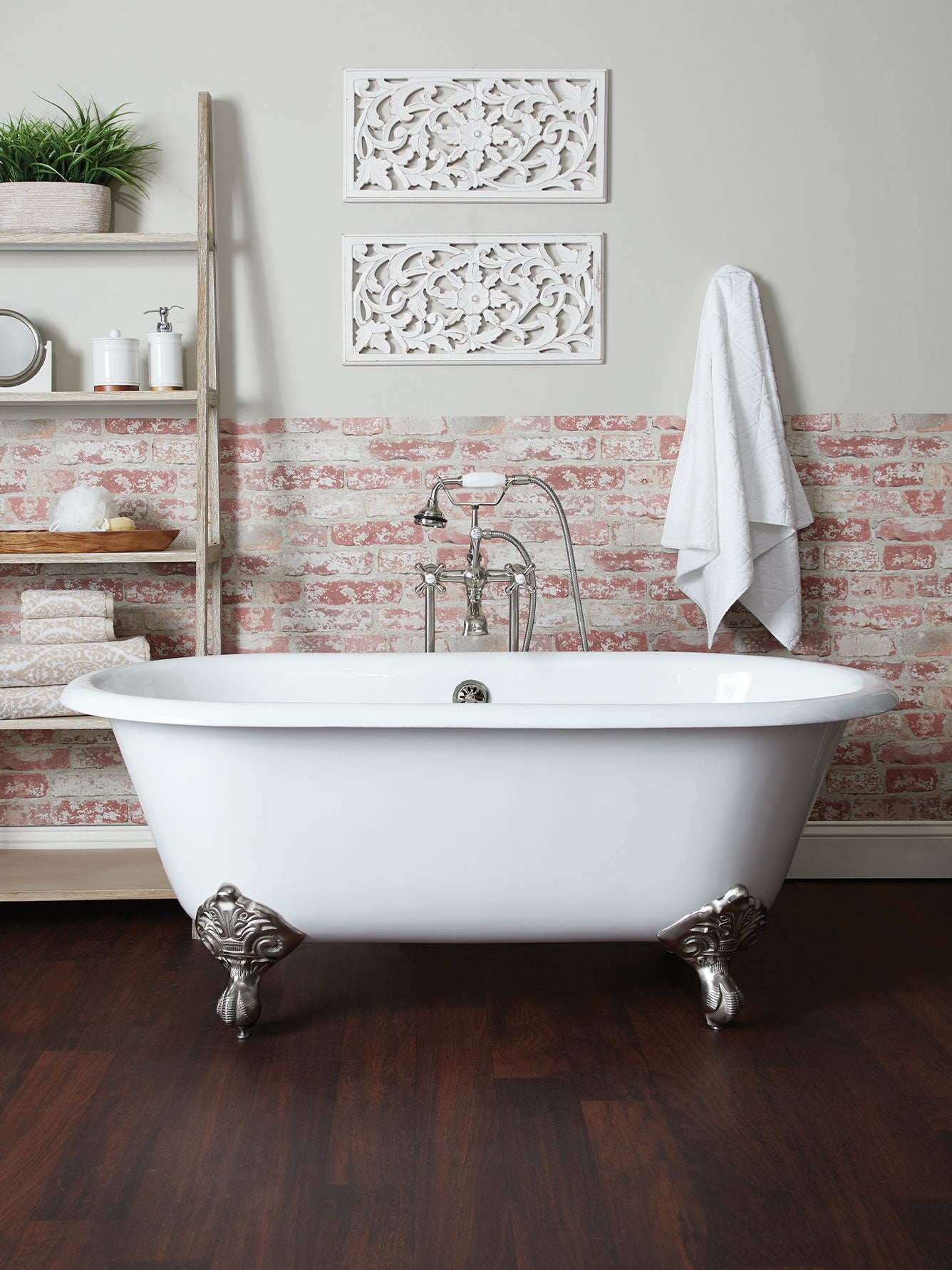White freestanding bathtub in a bathroom with decorative wall art and wooden floor.
