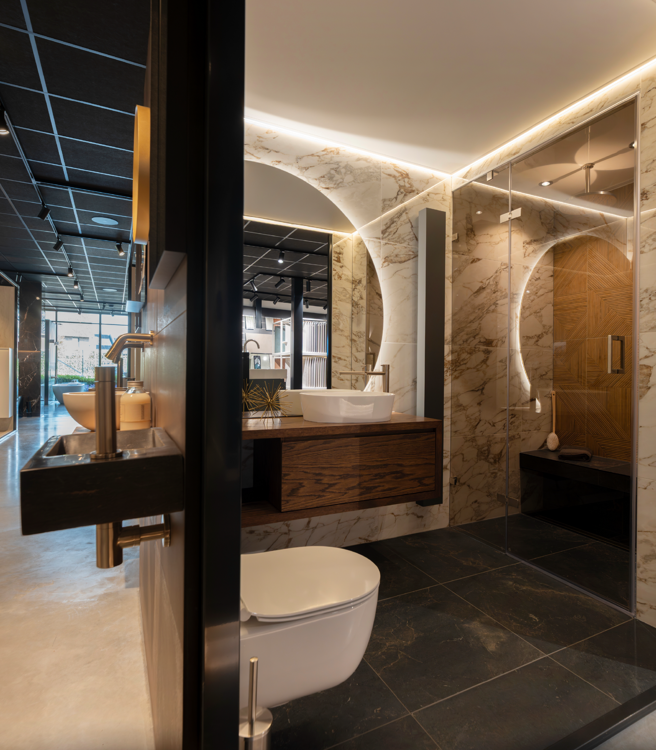 Modern bathroom with black tiles, white fixtures, and a large mirror.
